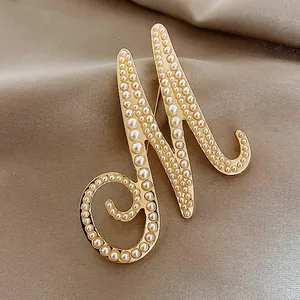 Detailed view of an elegant vintage pearl-encrusted letter M brooch jewelry.