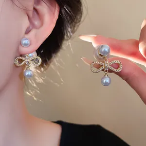 Primo piano di orecchini a fiocco placcati in oro con perle artificiali brillanti