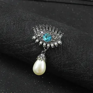 Close-up detail of a vintage evil eye brooch featuring blue crystal and a teardrop pearl
