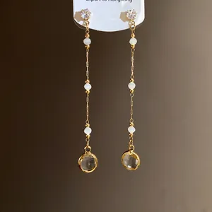 Nahaufnahme eleganter langer Ohrhänger mit facettierten runden Glasanhängern und Goldketten
