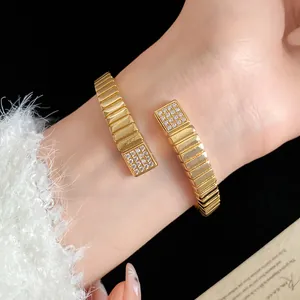 Close-up of 18k gold plated ribbed bangle with cubic zirconia stones on a wrist.