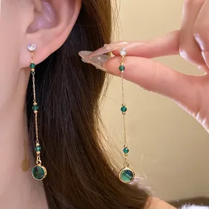 Nahaufnahme eleganter langer Quastenohrringe mit grünen Glasperlen und rundem Anhänger
