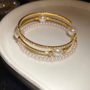 Elegant triple-layer pearl and diamond open cuff bracelet with a vintage luxury design