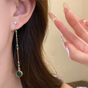 Nahaufnahme von Vintage-Quastenohrringen mit eleganten grünen Smaragd-Glaskugeln.