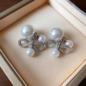 Dettaglio di eleganti orecchini a fiocco con perle bianche in una scatola regalo