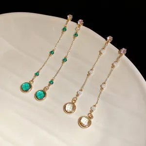 Detailansicht eleganter langer Quastenohrringe mit grünen und weißen Glassteinen.