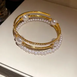 Elegant 3-layer gold plated open cuff bracelet featuring pearls and sparkling rhinestones.