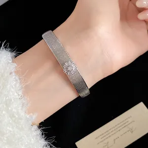 Close-up of elegant mesh bracelet with central zircon flower on wrist for women