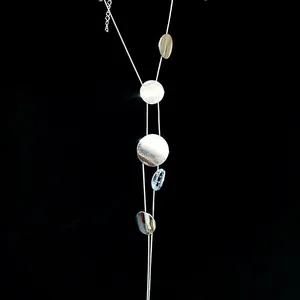 Detail view of a long silver tassel necklace with polished round metal disks