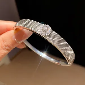Detailed close-up of a silver-toned textured bangle with a sparkling zircon flower motif