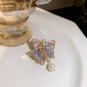 Close-up of vintage butterfly brooch featuring lavender enamel and a white pearl drop