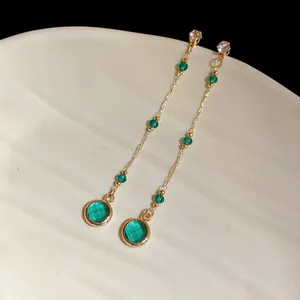 Nahaufnahme von eleganten Vintage-Quastenohrringen mit grünen Glasperlen und Goldketten