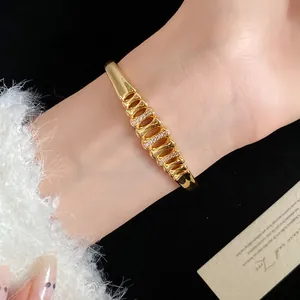 Detail shot of a luxury 18k gold plated geometric bangle with zircons on a wrist