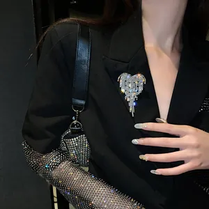 Close-up of a sparkling crystal heart tassel brooch pinned on a black blazer jacket