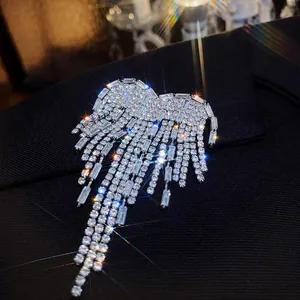 Close-up detail of sparkling rhinestone wing brooch with tassels on black blazer