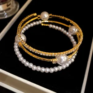 Close-up detail of a vintage three-layer gold-tone bracelet with pearls and rhinestones