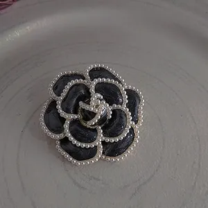Elegant vintage black camellia brooch with delicate pearl trim and classic flower design