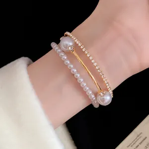 Close-up of elegant three-layer gold bracelet with white pearls and rhinestones on wrist