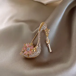 Detailed view of gold high heel shoe brooch with rhinestones and pink enamel flower
