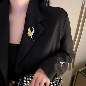 Elegant vintage leaf brooch featuring gold crystals pinned to a stylish black blazer lapel