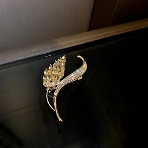 Detailed close-up of elegant gold-plated wheat leaf brooch decorated with sparkling crystals