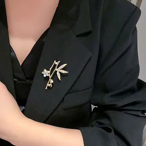 Elegant gold bamboo leaf brooch with sparkling rhinestones pinned on a black blazer