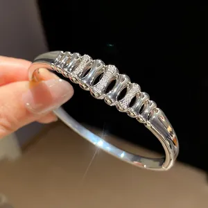 Close-up detail of silver geometric openwork bangle with sparkling inlaid zircon stones