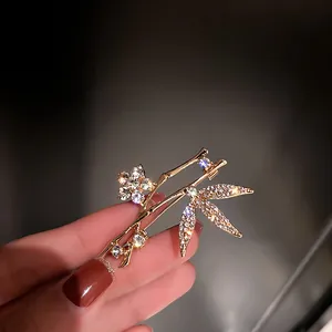 Detailed macro shot of an elegant gold-toned bamboo brooch with sparkling crystals.