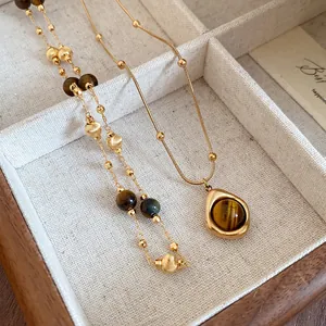 Primer plano de collar vintage de cuentas de ojo de tigre y colgante de gota dorado