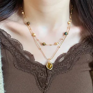 Detalle de collar de ojo de tigre con colgante de gota sobre un top de encaje marrón