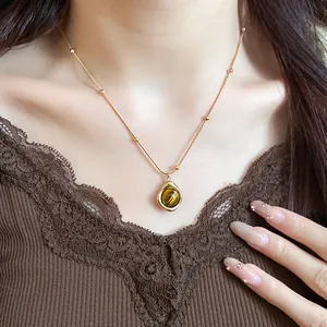 Primer plano de un collar de oro vintage con un colgante de gota de piedra ojo de tigre