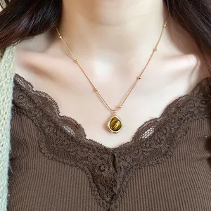 Detalle de un collar vintage con colgante de gota en ojo de tigre puesto en una modelo