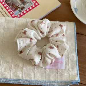 Close-up of a white fabric scrunchie with cute brown bear and floral prints for girls