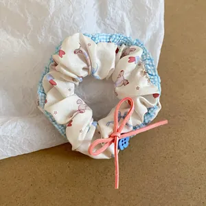Detail view of a Korean-style fabric scrunchie with cute rabbit prints and a pink bow.