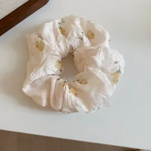 Close-up view of a soft fabric scrunchie featuring delicate yellow floral patterns