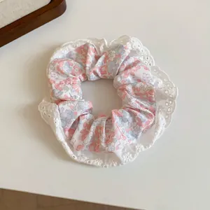 Close-up detail of a Korean style floral print cloth scrunchie with white lace trim.