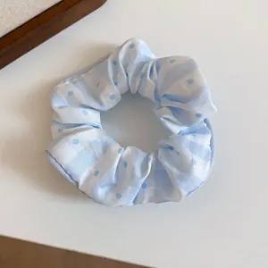 Close-up of a light blue striped fabric scrunchie with polka dots pattern