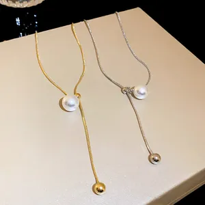 Close-up of elegant gold and silver snake chain necklaces with pearl tassel details