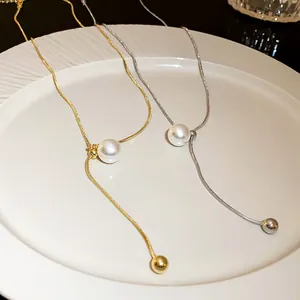 Detailed close-up of minimalist snake chain necklace with pearl and gold bead accents