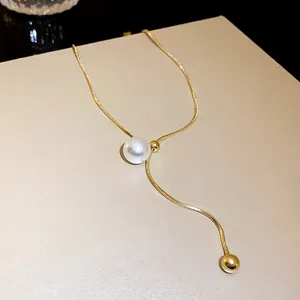 Close-up of elegant gold snake chain necklace with pearl and gold bead accents