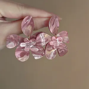 Close-up of pink marbled flower resin earrings with elegant vintage gold accents.