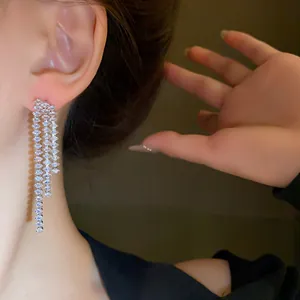 Detailaufnahme eleganter mehrsträngiger Kristall-Quastenohrringe am Ohr eines Models