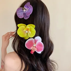 Vue détaillée de pinces à cheveux orchidées réalistes avec perles sur cheveux ondulés.