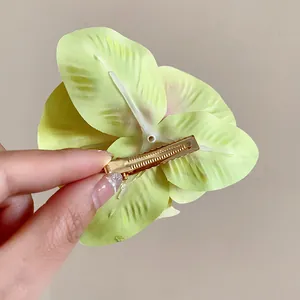 Détail de la vue arrière d'une pince à cheveux orchidée vert clair avec clip doré