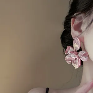 Close-up of large pink marbled resin flower earring worn on model.