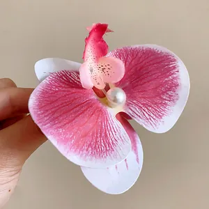 Gros plan d'une pince à cheveux orchidée rose avec une perle blanche au centre.