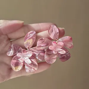 Close-up detail of handmade pink resin flower earrings featuring a marble ink pattern