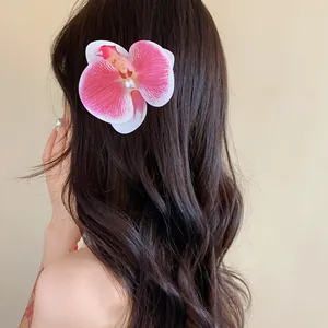 Gros plan d'une pince à cheveux orchidée rose avec perle sur cheveux ondulés
