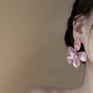 Detailed side profile view of pink marble resin flower stud earrings worn by a model