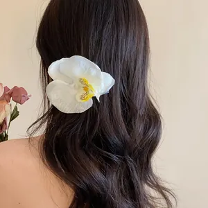 Détail d'une élégante barrette fleur d'orchidée blanche sur de longs cheveux sombres